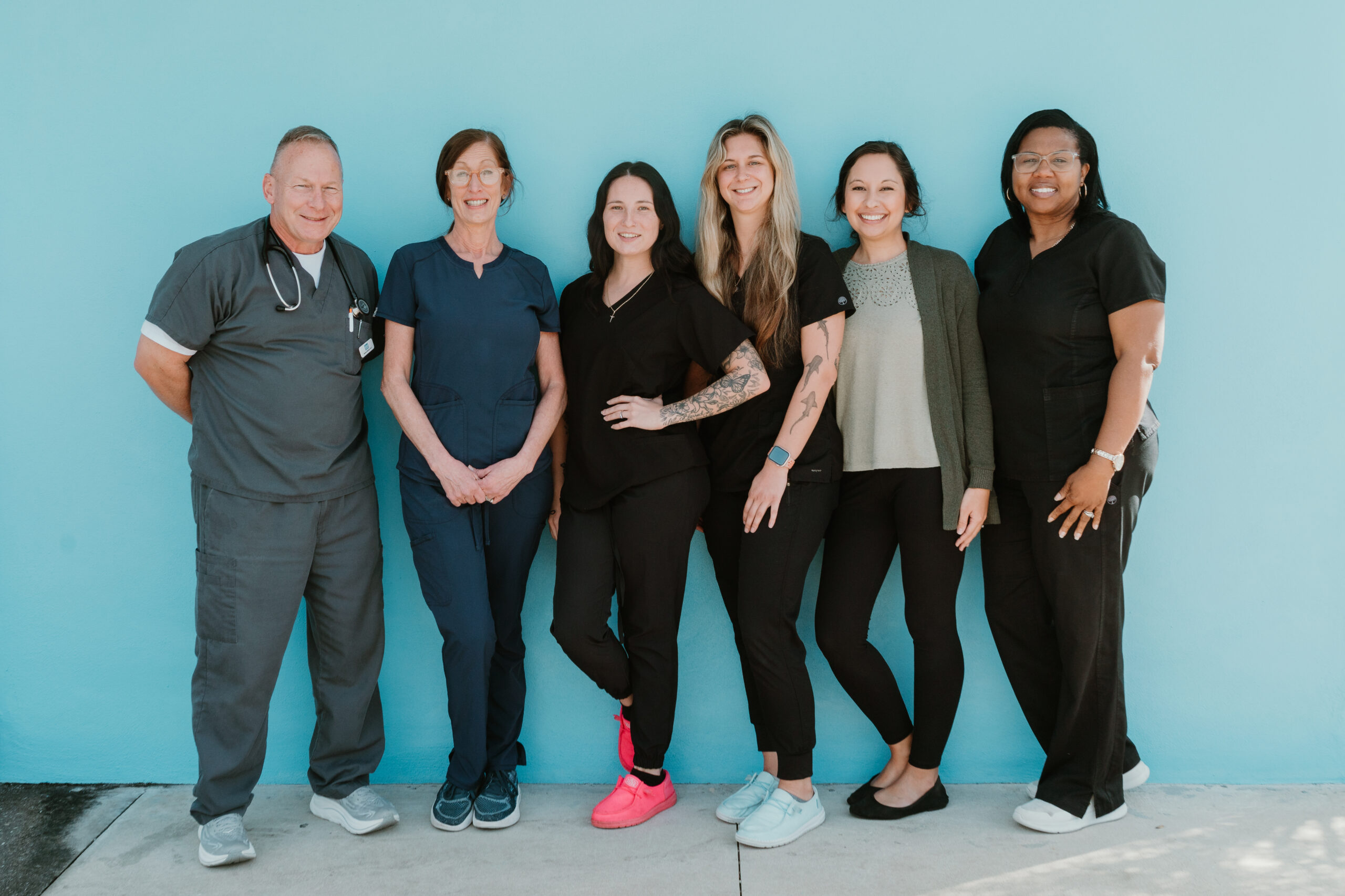 Island Doctors Arricola staff standing together against a blue wall